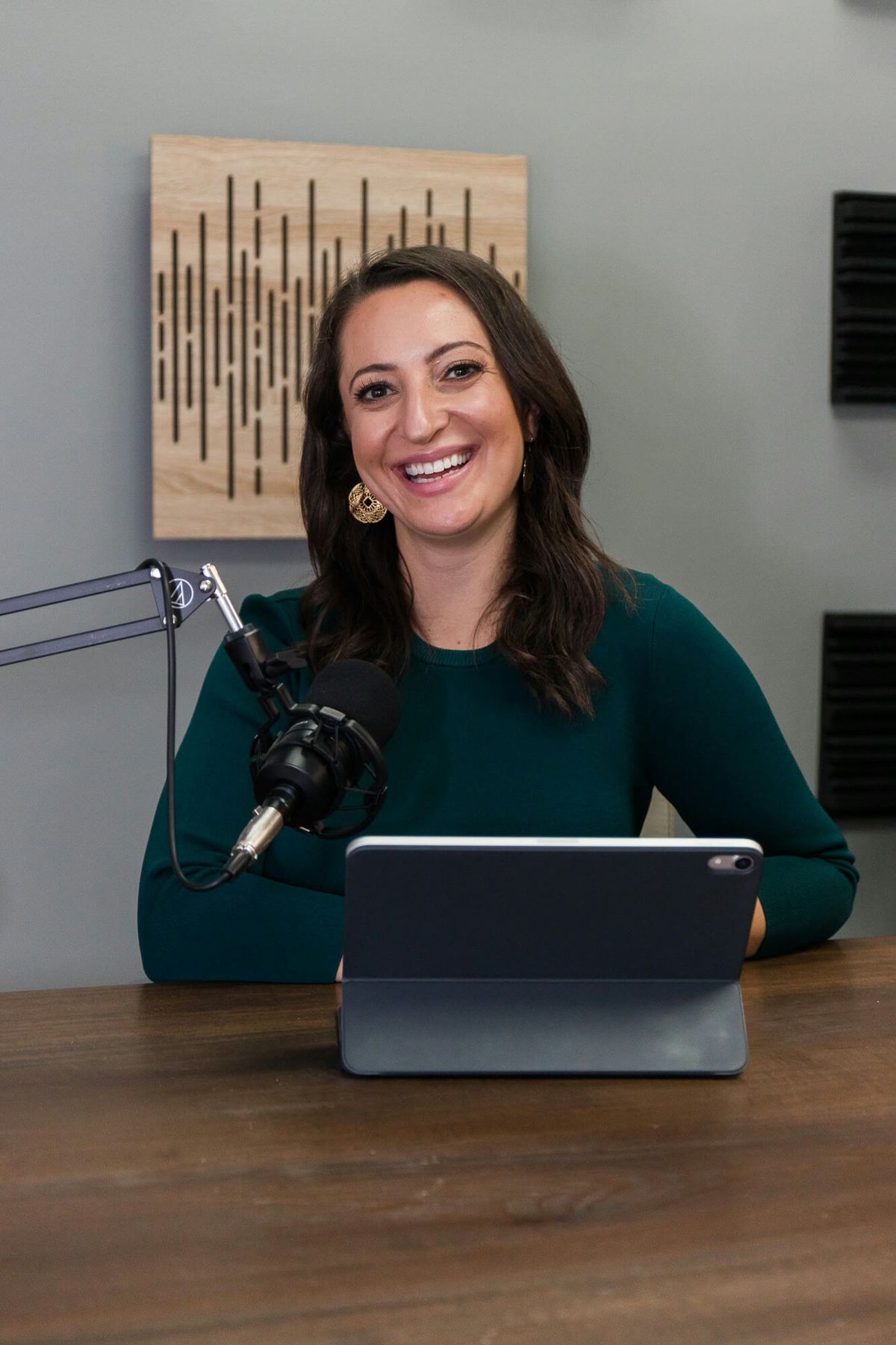 Lauren Goldstein smiling behind a podcast microphone in her studio